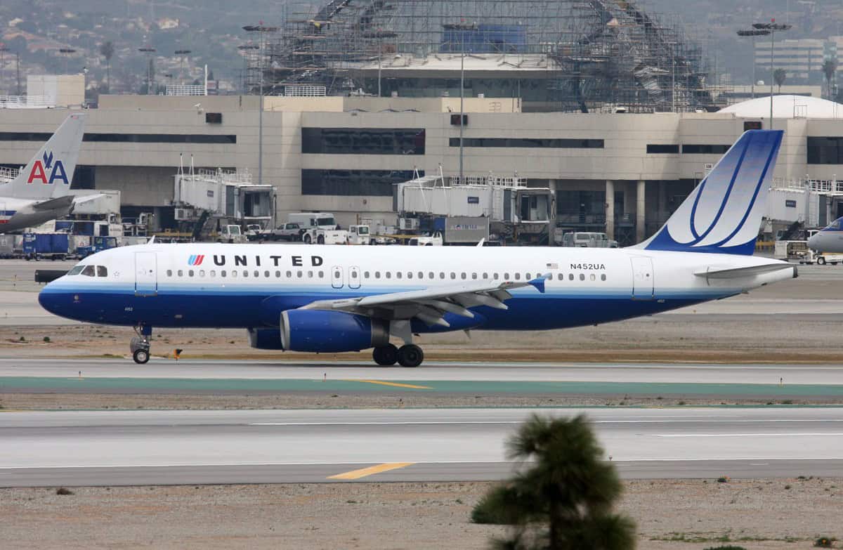 United Airlines Airbus A320 N452UA in the older blue and white livery taxiing past a terminal at Los Angeles