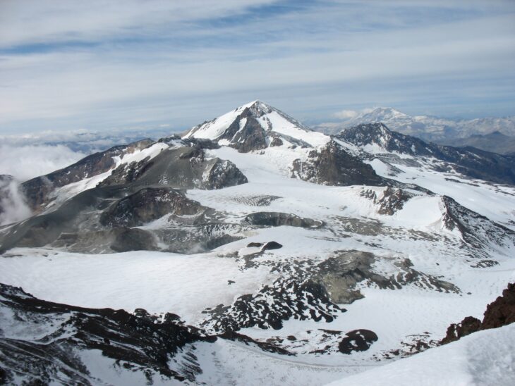 Snow-covered summit of Planchón-Peteroa in the Andes under a partly cloudy sky