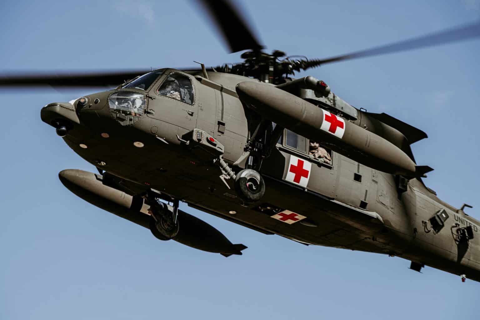 US Army UH-60 Black Hawk medevac helicopter banking low overhead against a blue sky