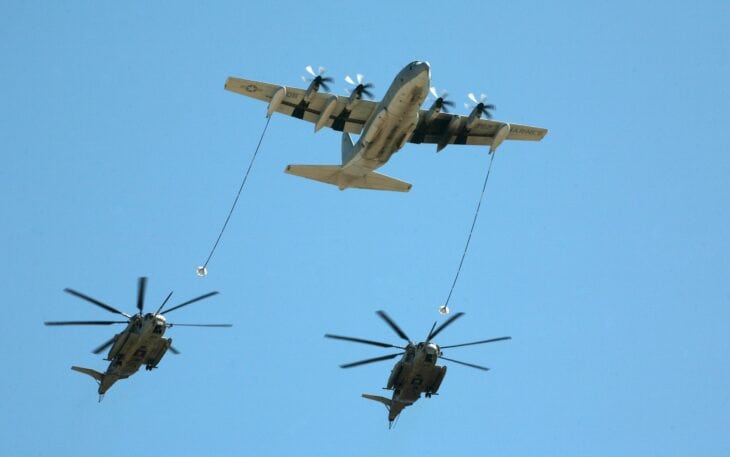 Marine Corps KC-130J Hercules trailing two refueling hoses to a pair of CH-53E Super Stallions