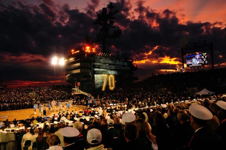 Sunset behind the island of USS Carl Vinson as a crowd fills the flight deck for the 2011 Carrier Classic basketball game