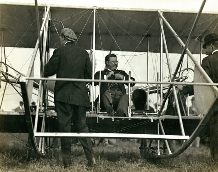 Theodore Roosevelt seated in the Wright Model B at Kinloch Field in October 1910 before his first airplane ride, with pilot Arch Hoxsey standing at left