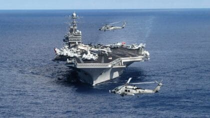 USS Theodore Roosevelt (CVN-71) steaming head-on in the Atlantic with two HH-60H Seahawk helicopters hovering off her bow