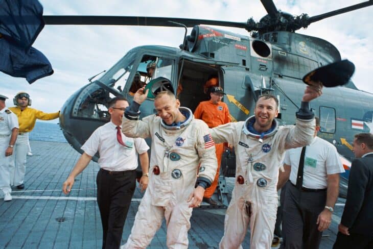Gemini 12 astronauts Jim Lovell and Buzz Aldrin waving beside a recovery helicopter on the deck of USS Wasp (CV-18)
