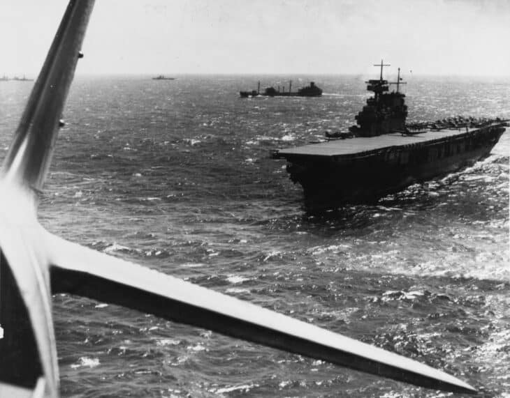 USS Yorktown CV-5 at sea in early 1942 with aircraft ranged on her flight deck, photographed from a torpedo plane just after takeoff