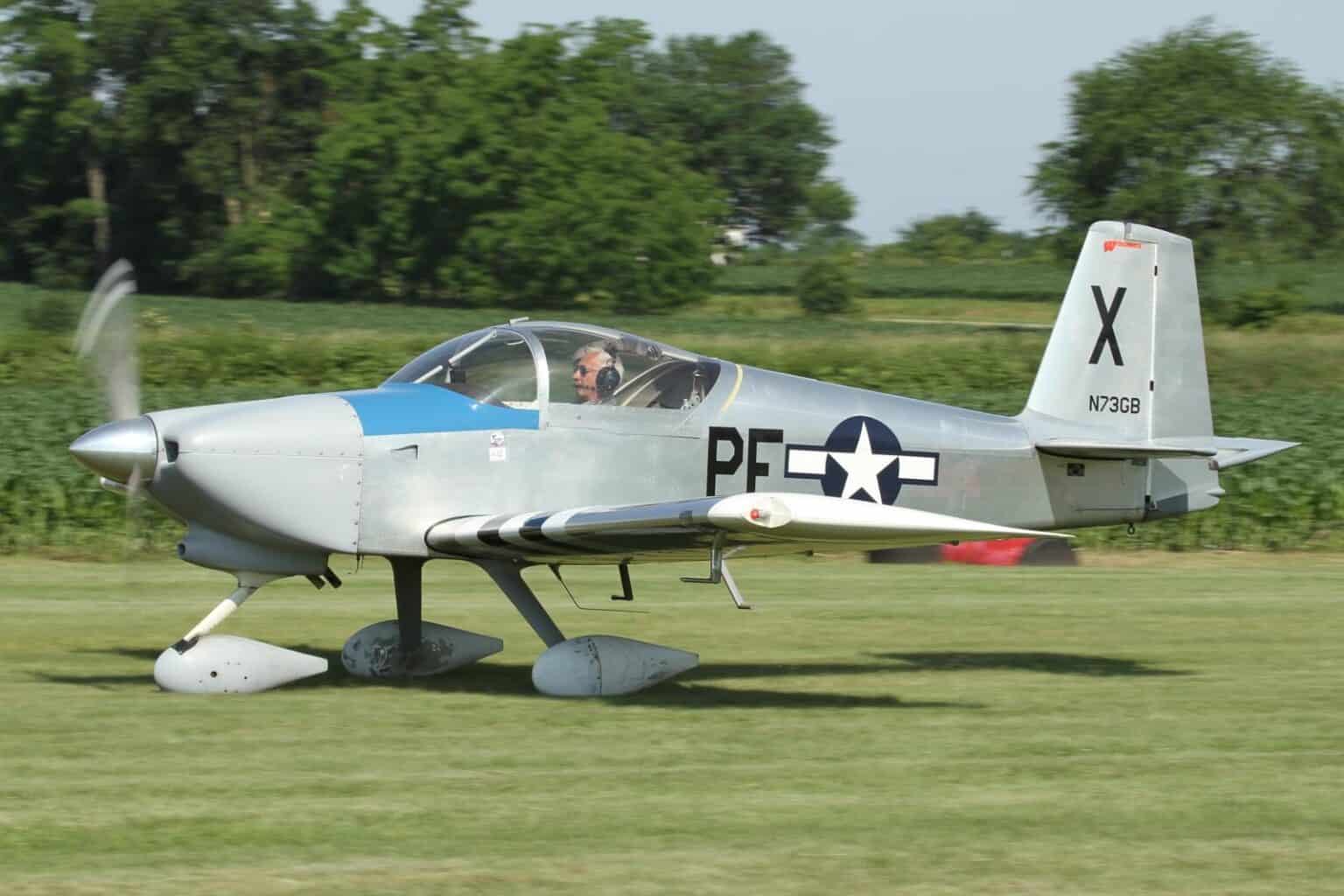 Silver Van's RV-7A N73GB in World War II-style markings taxiing on grass with its propeller turning