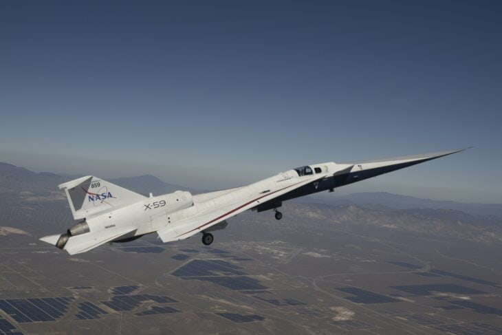 NASA X-59 climbing away in a banked turn, long slender nose pointing ahead